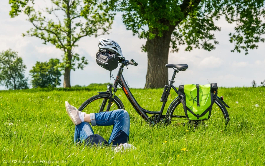 Frau liegend auf Wiese, daneben Fahrrad Foto: AG LGS-Route und Fotografie Golz